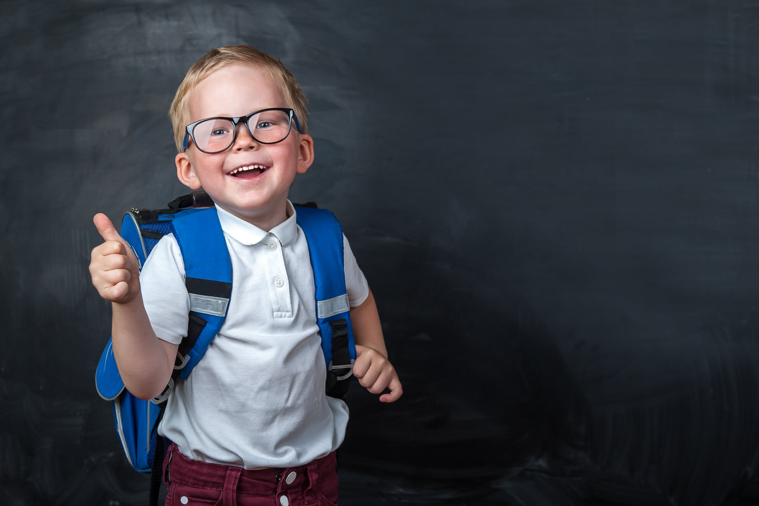 Child with backpack giving thumbs up
